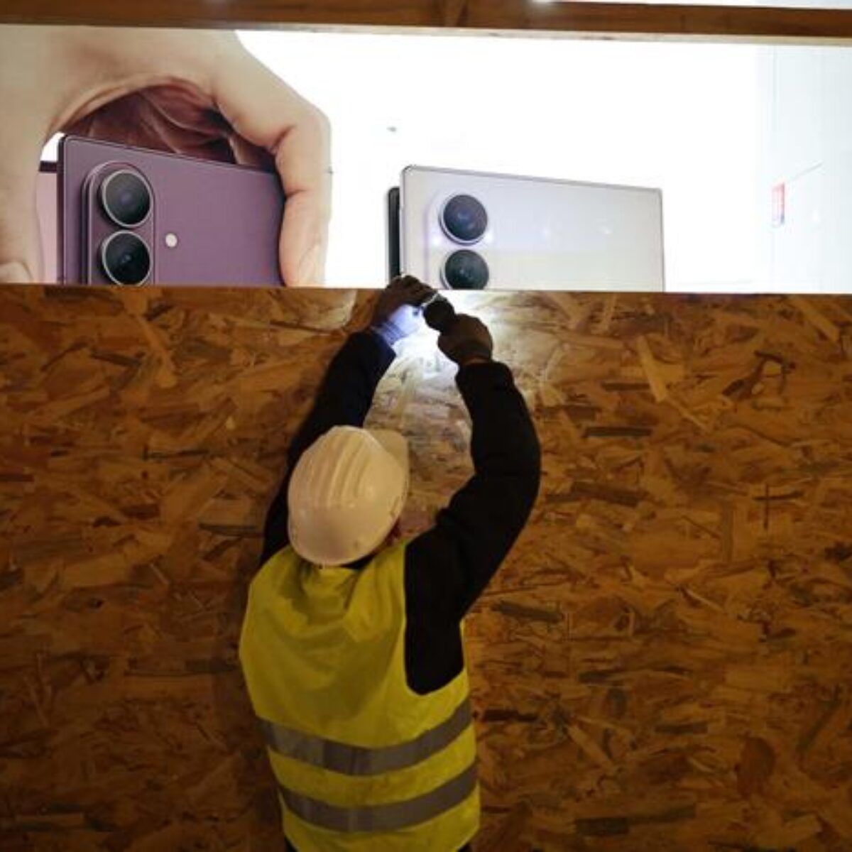 Um trabalhador instala um painel de madeira para tapar a vitrine da loja Samsung antes de uma manifestação planejada para 24 de outubro, no Boulevard Malesherbes, no centro de Paris, em 23 de outubro de 2026, após as manifestações do último fim de semana que degeneraram na pior violência de rua em anos. A França irá mobilizar cerca de 70 mil agentes de segurança em todo o país para novos protestos neste fim de semana, disse o Ministro do Interior em 23 de outubro, alertando que apelos à violência e aos saques já circulavam nas redes sociais. (Foto de SIMON WOHLFAHRT/AFP)