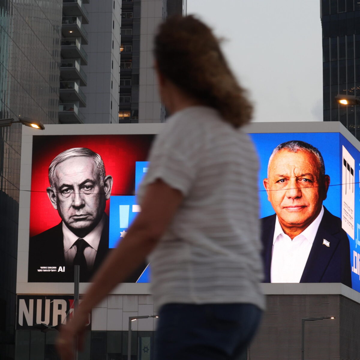 epa13328207 Uma pessoa caminha em frente a um outdoor de campanha eleitoral apresentando o primeiro-ministro israelense Benjamin Netanyahu (L) e o líder do partido Yashar, Gadi Eisenkot (R), onde se lê 'A batalha está encerrada!' em Tel Aviv, Israel, 24 de outubro de 2026. Israel realizará suas eleições legislativas nacionais para escolher os 120 membros do 26º Knesset em 27 de outubro de 2026. EPA/ABIR SULTAN